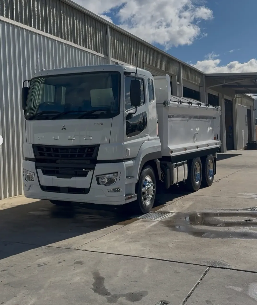 A white tipper truck cleaned down outside a workshop
