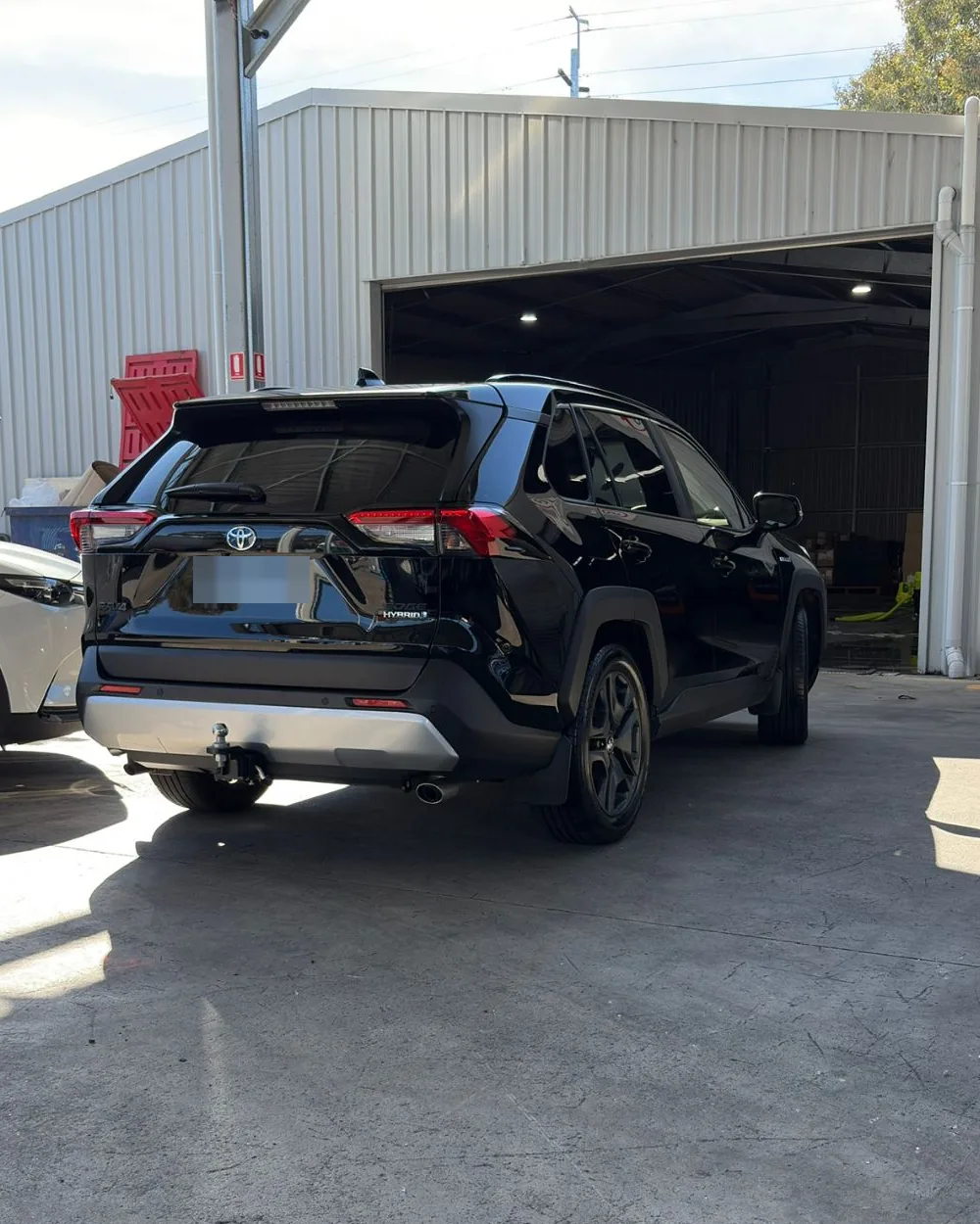 Black Toyota RAV4 Hybrid, washed and dried, outside a shed
